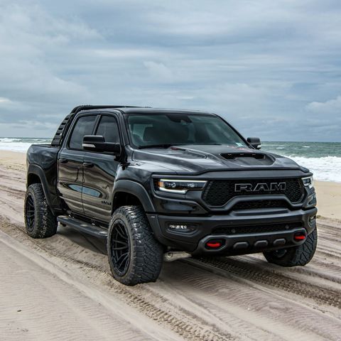 a black truck is driving on the beach