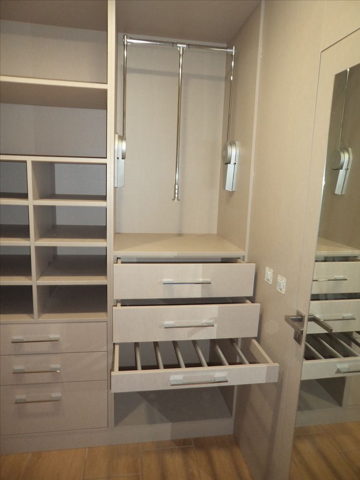 an empty walk in closet with drawers and mirrors