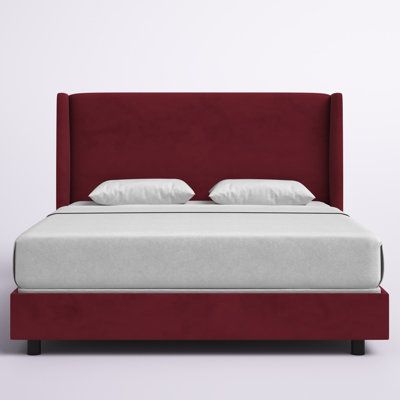 a bed with white pillows and red headboard