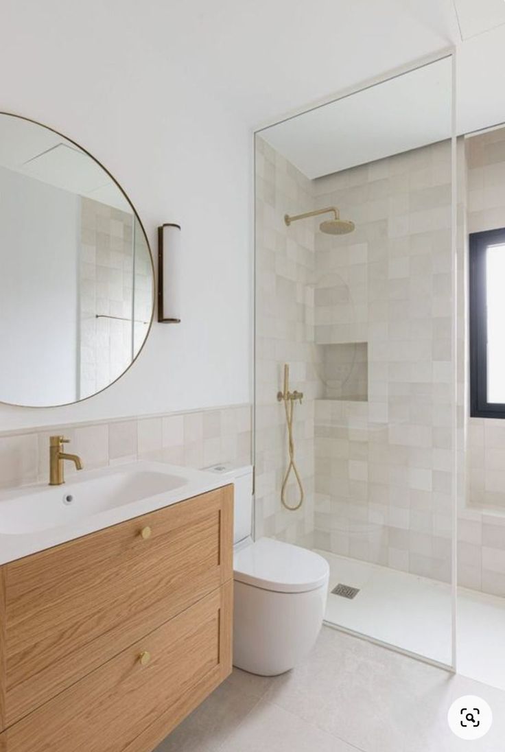 a bathroom with a sink, toilet and shower stall in the background is a large mirror