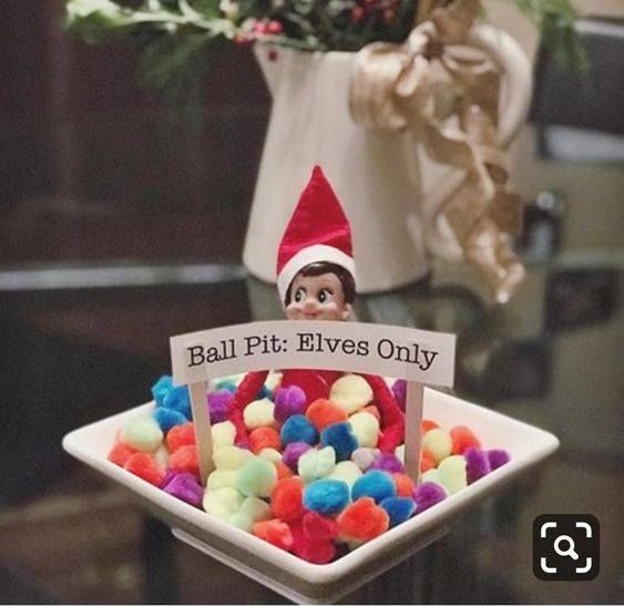 an elf is sitting in a bowl filled with pom - poms and a sign that says ball pit elves only