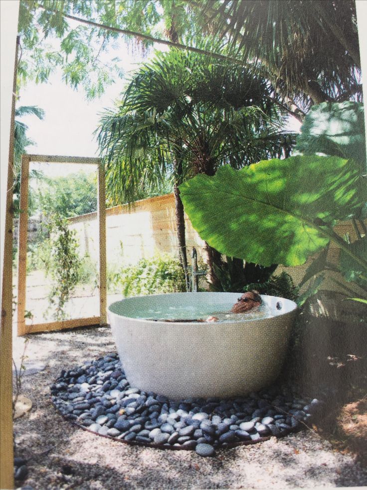 an outdoor bathtub surrounded by plants and rocks