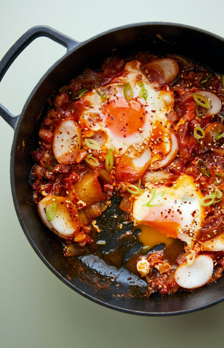 an iron skillet filled with eggs and other food on top of a white table