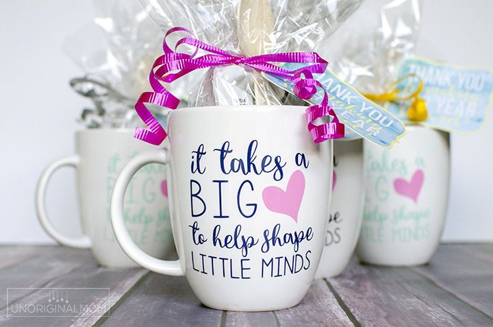 three coffee mugs with candy wrapped in cellophane and tied to them are sitting on a wooden table