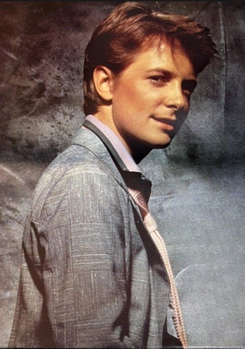 a young man wearing a suit and tie posing for a photo in front of a grungy background