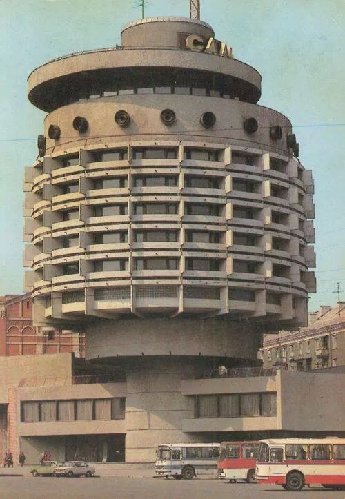 a large building with many windows and balconies on the top, surrounded by cars