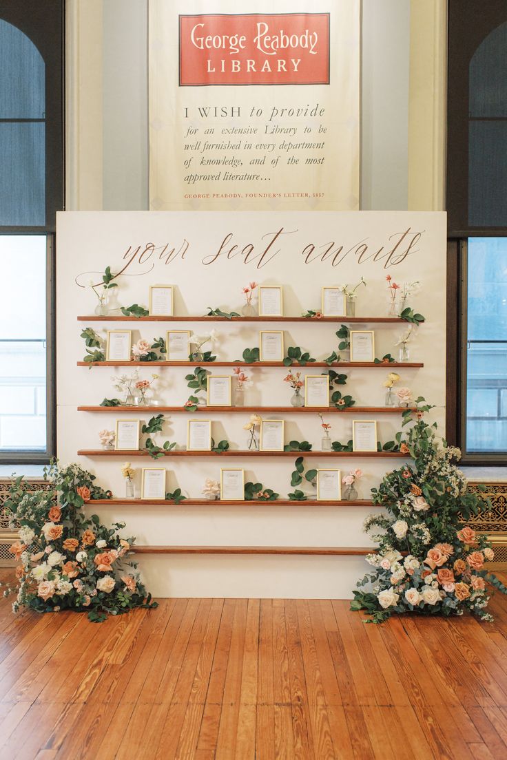 an arrangement of flowers and candles on display in front of a sign