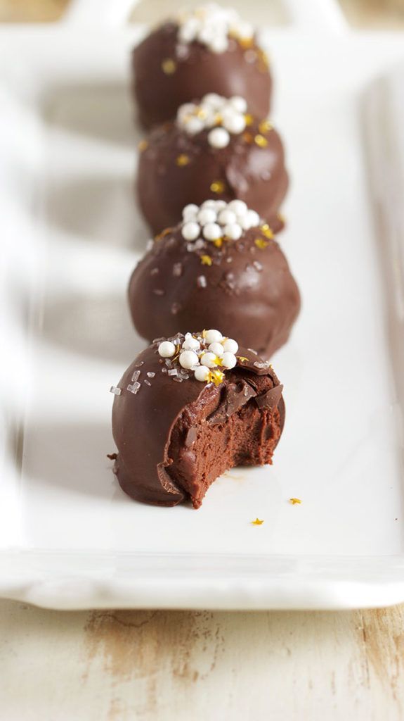 chocolate truffles with white and gold sprinkles lined up on a plate