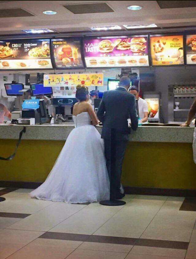 a bride and groom are standing in front of the counter at a fast food restaurant