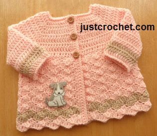 a crocheted sweater with a small dog on the front and side, sitting on top of a wooden table