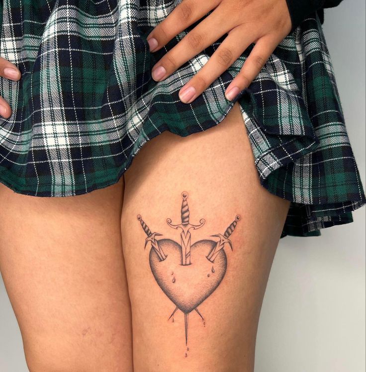 a woman's thigh with a tattoo on it that has a heart and an arrow