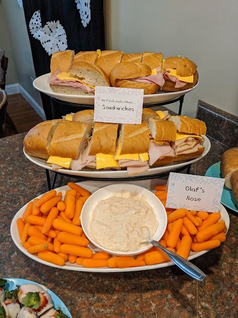 sandwiches, carrots and dip are displayed on three platters