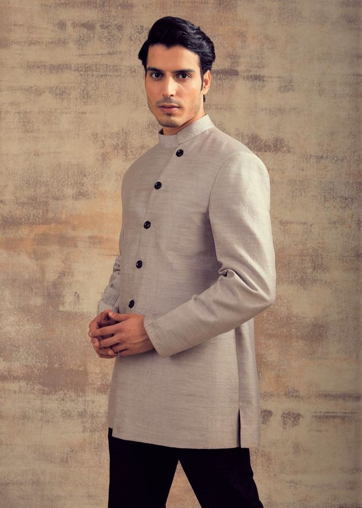 This Blue Color Indo Western Jacket is in Raw Silk with an asymmetrical button line. Linin of the jacket kept in black contrast with trousers. This Indo Western Jacket can also be paired with any black colour Kurta Sets. Perfect fit for any wedding function. Brand: Panache Haute Couture Availability: Online and In-store Delivery Time: 4-6 Weeks Fabric: Jacket - Dupion, Trousers: Raw Silk Customisation: Colour Options Available. For more colour options please contact our team through WhatsApp+614 Formal Long Sleeve Sets With Hidden Button Closure, Semi-formal Long Sleeve Suiting Fabric Set, Tailored Tuxedo With Button Closure For Wedding, Long Sleeve Single Breasted Wedding Sets, Tailored Long Sleeve Sets For Groom, Long Sleeve Wedding Tuxedo With Button Closure, Tailored Long Sleeve Wedding Sets, Long Sleeve Sets With Button Closure For Wedding, Long Sleeve Wedding Set With Button Closure