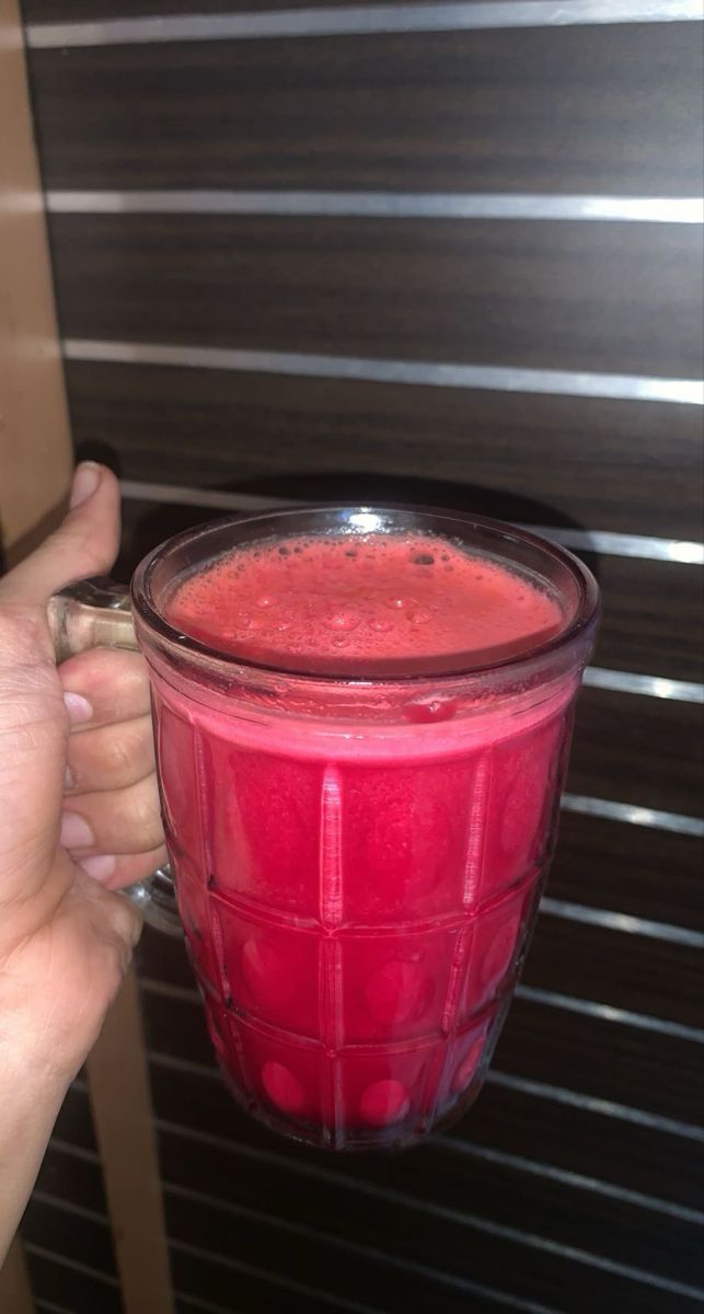 a hand holding a blender filled with red liquid