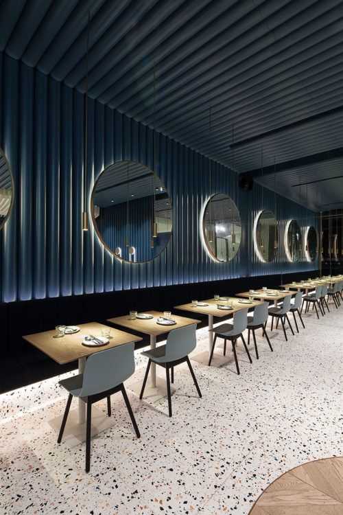 an empty restaurant with round mirrors on the wall and long tables set up in front of them