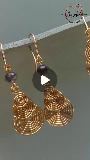 two pairs of gold earrings hanging from hooks on a hook - off wire, with a black bead in the middle