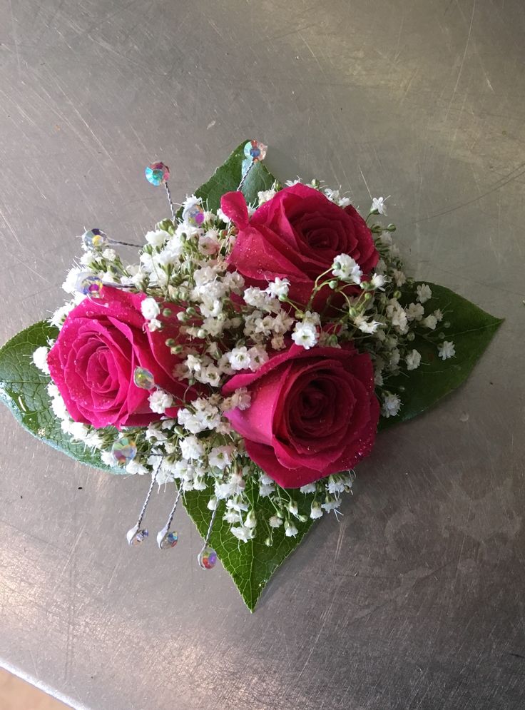 a bouquet of pink roses and baby's breath on top of a metal table