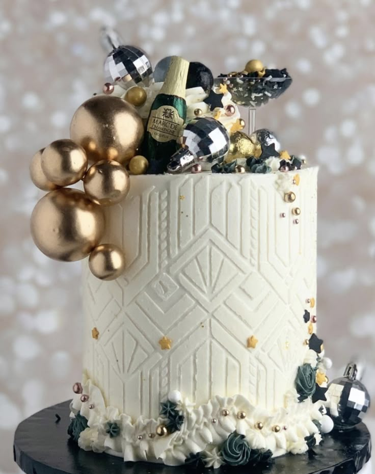 a white and gold decorated cake on a black stand with some balloons in the air