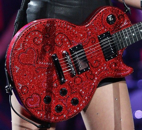 a woman holding a red guitar on stage