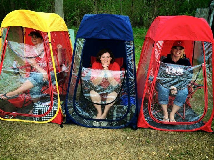 three people sitting in portable toilets on the grass