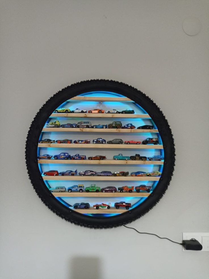 there is a round display with cars in it on the wall above a table and lamp