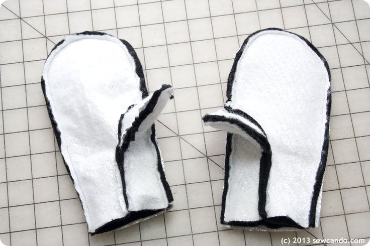 two white mitts sitting on top of a tile floor next to each other with black trim