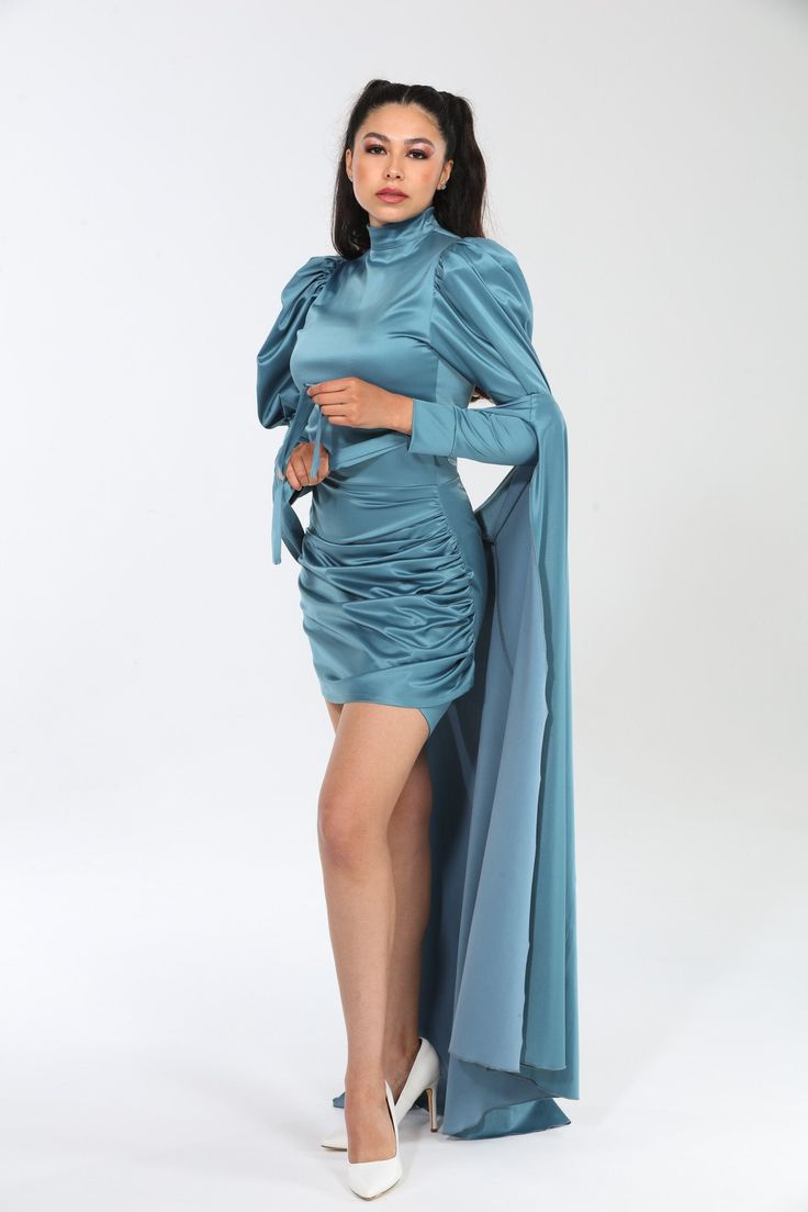 Crafted from a premium blend of 60% polyester, 37% cotton, and 3% spandex, the Genesis dress embodies luxury with its Dolce Satin fabric, offering a smooth, slightly stretchy feel that drapes beautifully and moves with grace. Designed to flatter, its silhouette hugs curves elegantly, enhanced by dramatic puff sleeves and a flowing cape that adds sophistication and movement. Versatile and effortlessly chic, the Genesis dress transitions seamlessly from day to night, whether styled with heels and Fitted Pre-draped Long Sleeve Maxi Dress, Pre-draped Ruched Dresses For Date Night, Fitted Long Sleeve Pre-draped Evening Dress, Pre-draped Mini Dress For Gala, Pre-draped Draped Dress For Night Out, Pre-draped Satin Dresses With Draped Sleeves, Silk Mini Dress With Draped Sleeves, Pre-draped Ruched Mini Dress For Gala, Fitted Pre-draped Knee-length Dress