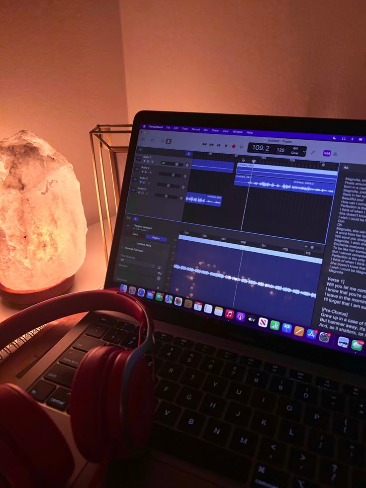 a laptop computer sitting on top of a desk next to a rock and headphones