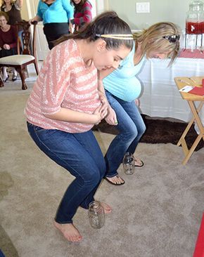 two women are playing with an interactive device in a room full of other people and one woman is looking at the screen