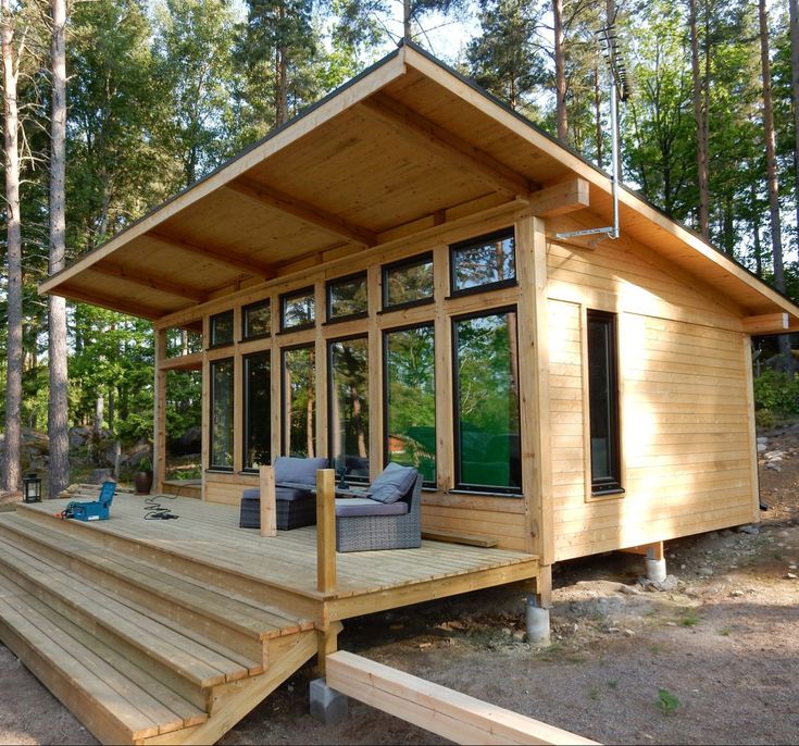 a small wooden cabin in the woods with stairs leading up to it's deck