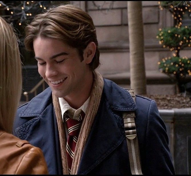 a man in a trench coat and tie smiles at another woman who is wearing a brown leather jacket