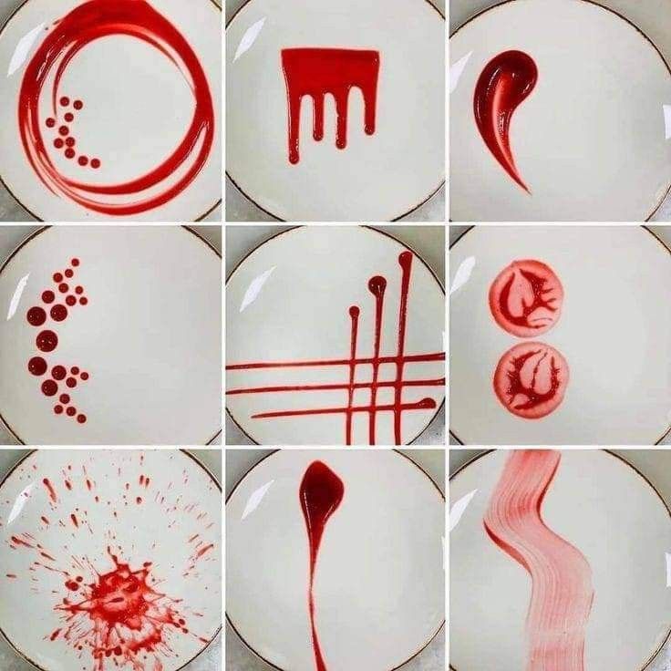 different plates with red paint on them and some utensils stuck to the plate