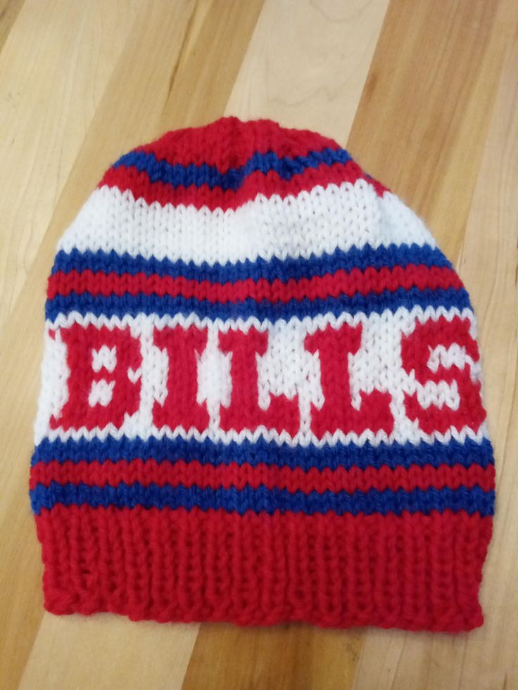 a red, white and blue knitted beanie sitting on top of a wooden floor