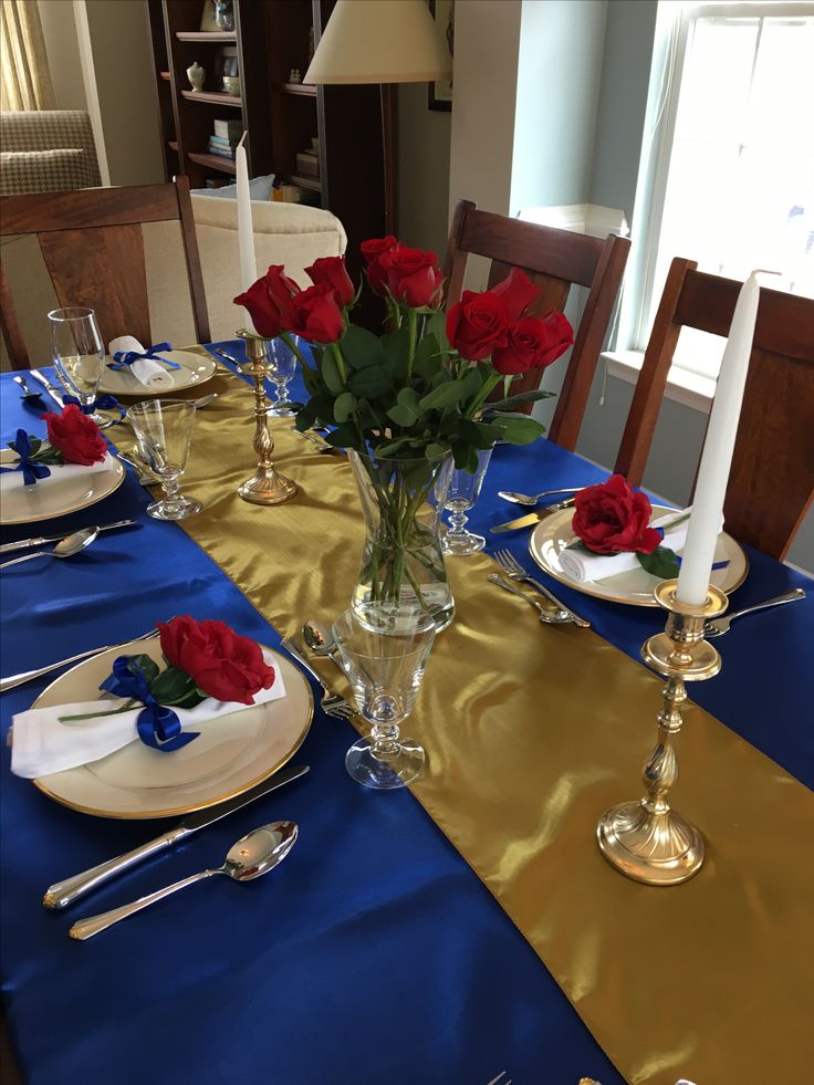 the table is set with red roses in a vase