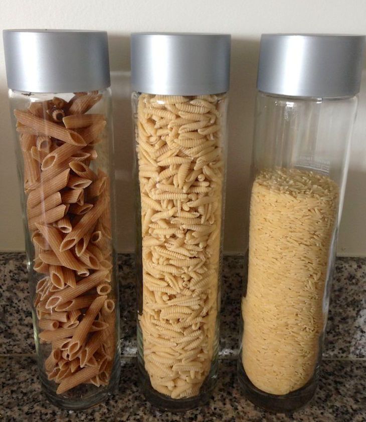 three glass containers filled with different types of pasta in them on a granite countertop