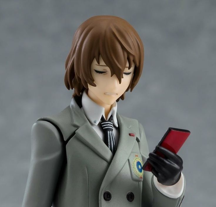 a figurine holding a cell phone in his right hand and wearing a suit