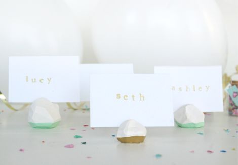 three place cards sitting on top of a table with confetti and balloons in the background