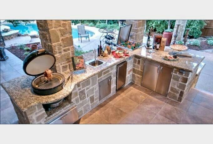 an outdoor kitchen with granite counter tops and stainless steel appliances