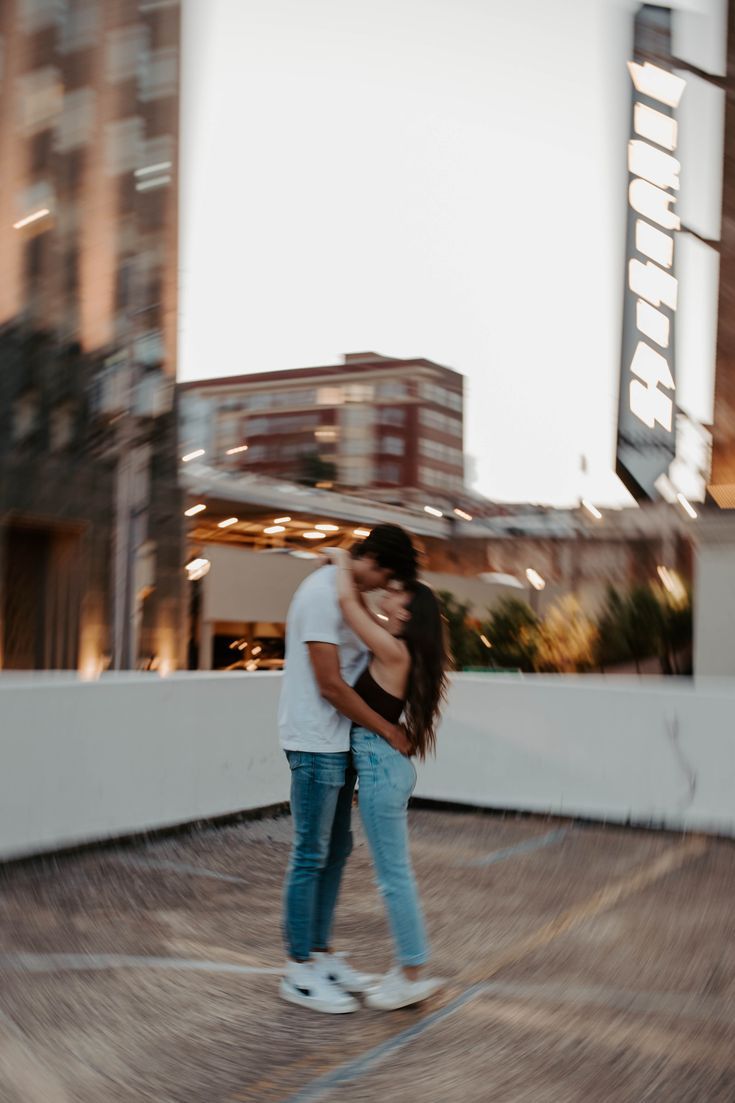 a man and woman standing next to each other on top of a roof in front of tall buildings