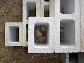 cinder blocks stacked on top of each other with rocks in the middle and one rock sticking out of them