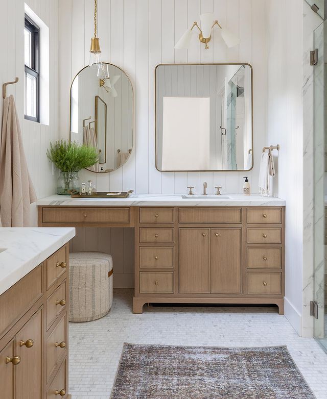 a bathroom with two sinks, mirrors and a rug on the floor in front of it