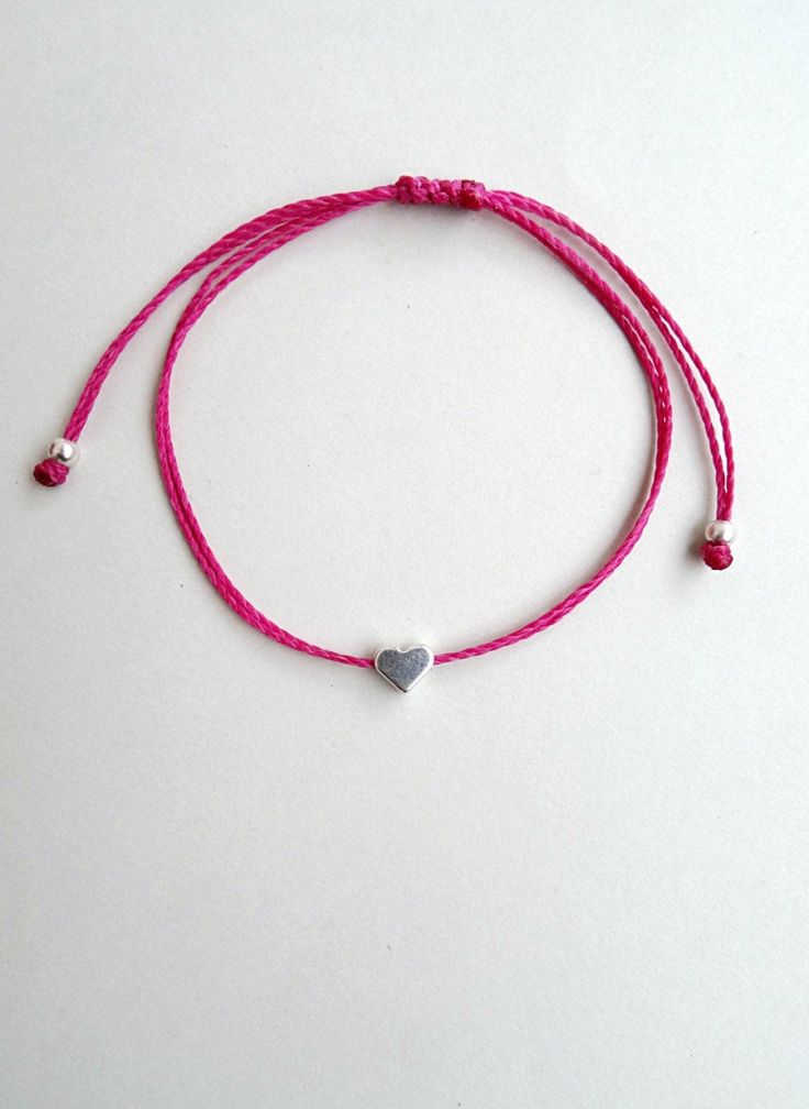 a pink string bracelet with a heart charm