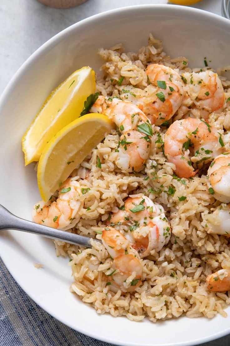 shrimp and rice with lemon wedges in a white bowl