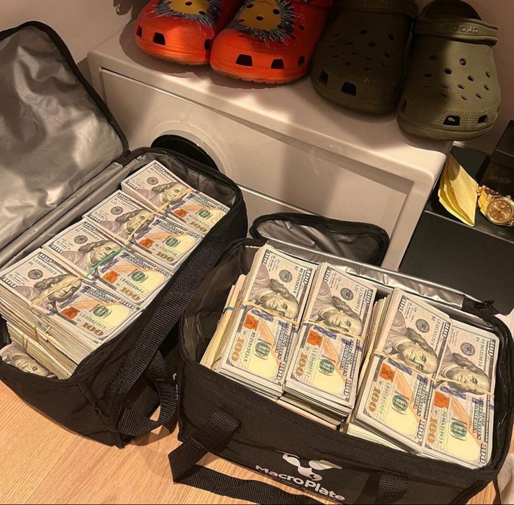 two suitcases filled with money sitting on top of a wooden floor next to shoes