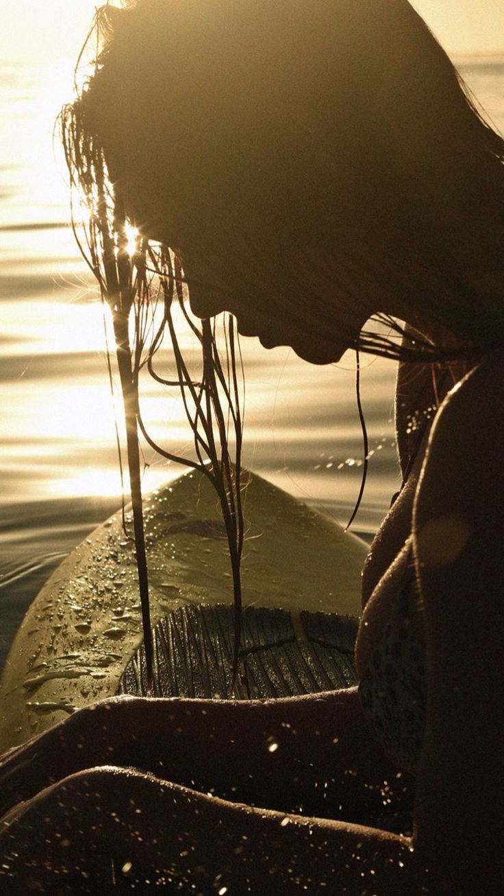 a woman sitting on top of a surfboard in the water