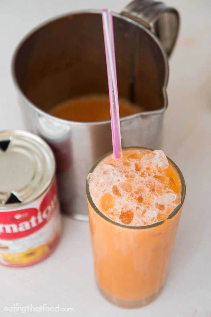 an orange drink in a glass next to two cans