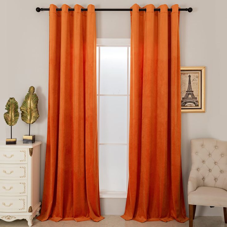 an orange curtain hangs in front of a window with a chair and potted plant