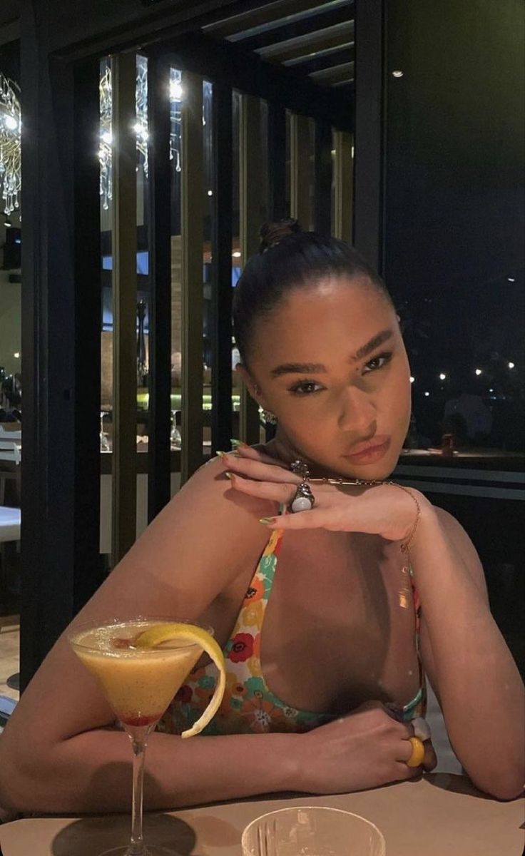 a woman sitting at a table with a drink in front of her