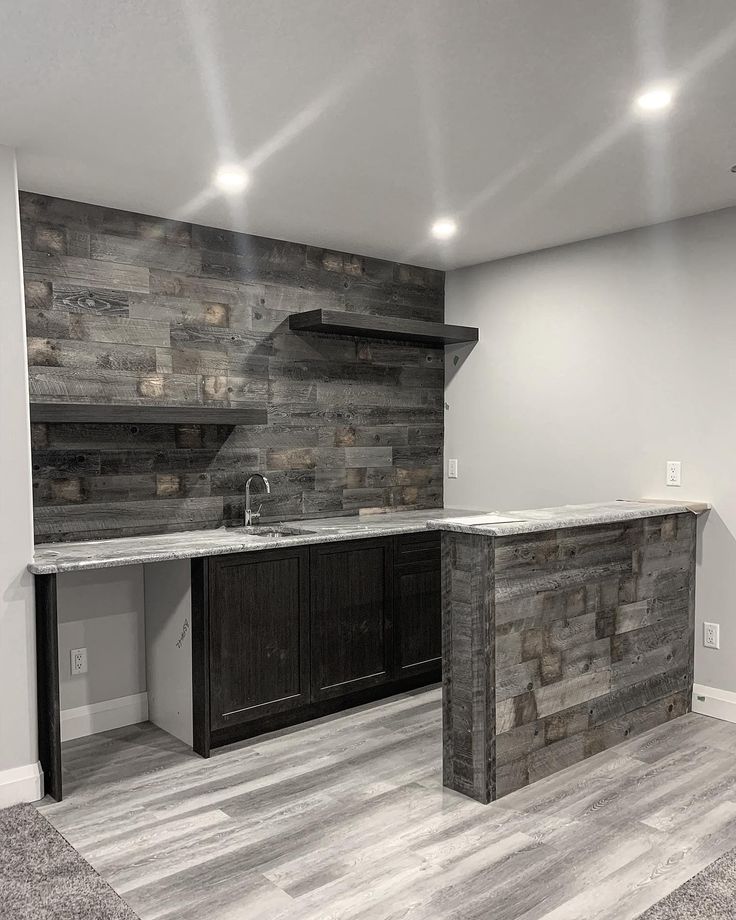 an empty kitchen with wood paneling on the walls and counter tops, in a basement