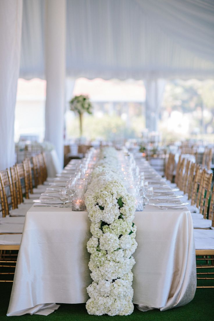 the table is set with white flowers and place settings for guests to sit down at